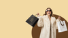 Woman in a white fur coat holding shopping bags with a brand logo on a beige background